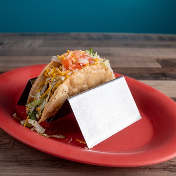 A crispy taco filled with lettuce, cheese, and diced tomatoes, served on a red plate.