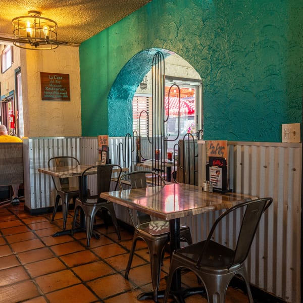 Interior of La Casa del Rey Mexican Restaurant with teal walls, tiled floors, and empty tables.
