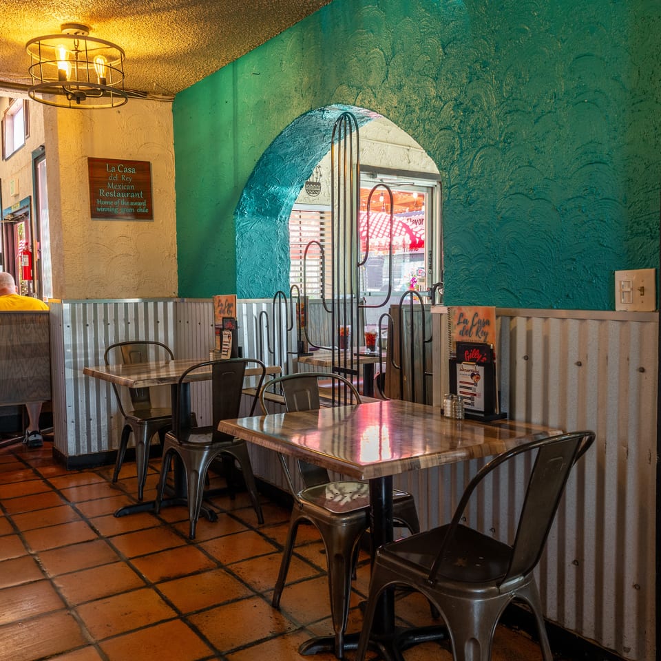 Interior of La Casa del Rey Mexican Restaurant with teal walls, tiled floors, and empty tables.