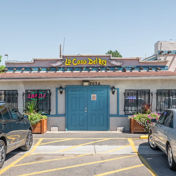 The exterior of La Casa Del Rey restaurant with blue doors, an "Open" sign, and parked cars.