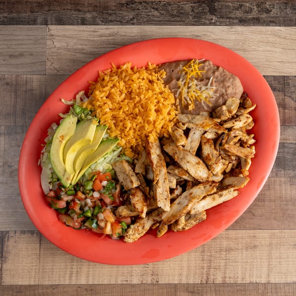 Grilled chicken strips, rice, refried beans, avocado, pico de gallo, and lettuce on a red plate.