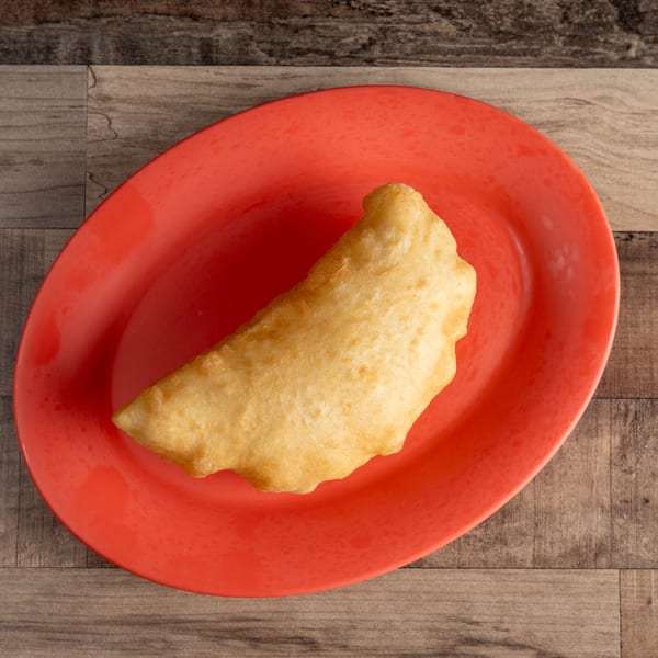Golden brown fried dough on a bright red oval plate, against a rustic wooden table.